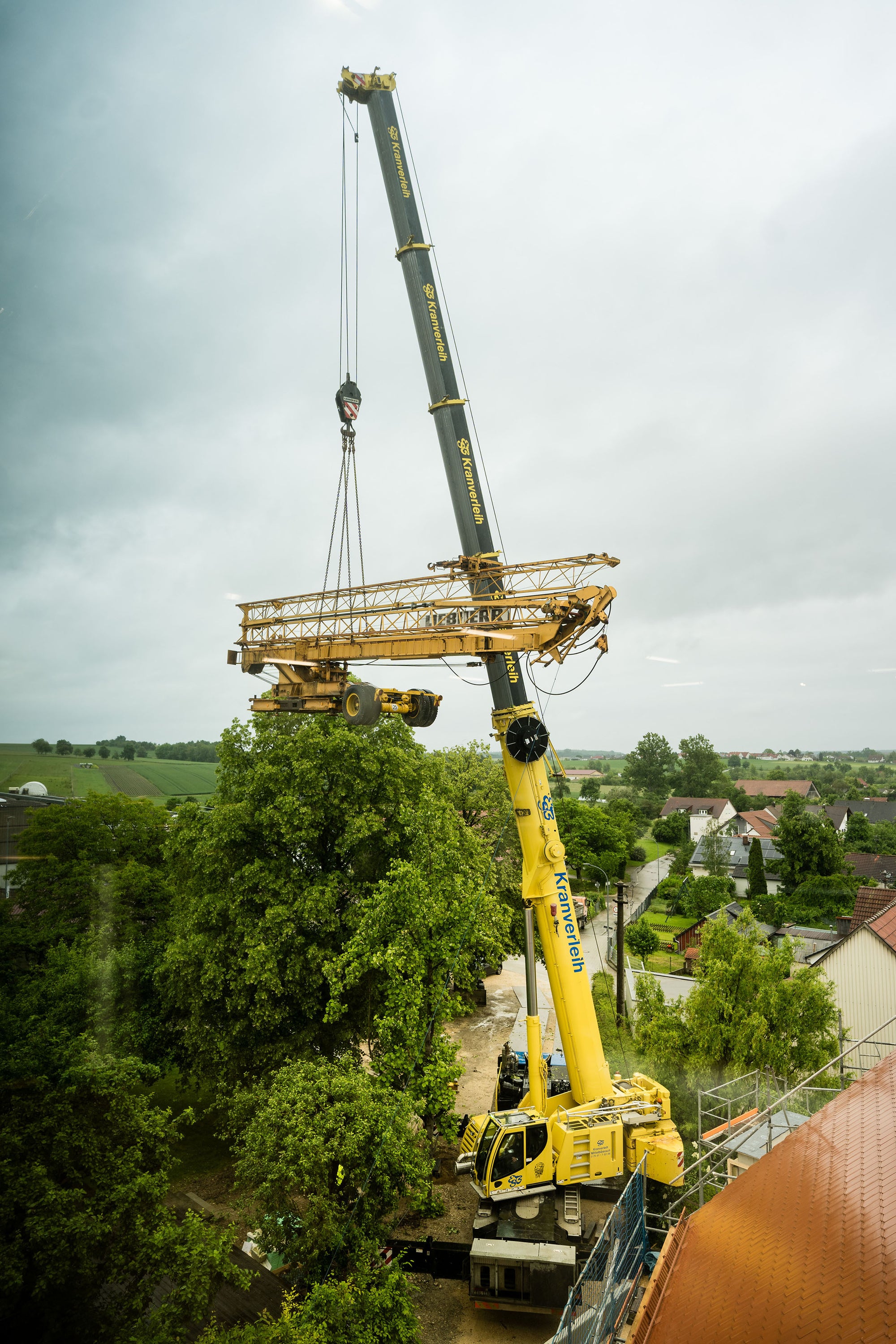 Mobile Crane Lifts Construction Crane Over Tree Tops