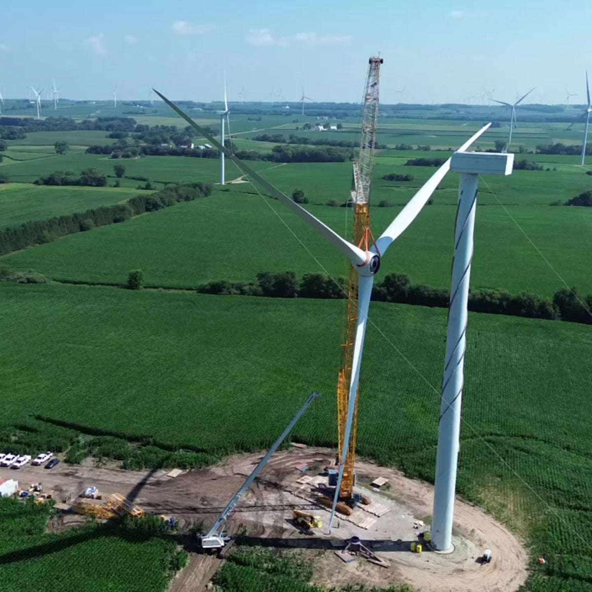Wind turbine under construction with a crane in a green field