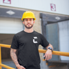 Man at work wearing a yellow hardhat and a black craneaholic t shirt with the C logo DTG printed on the front in white