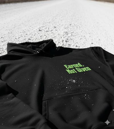 Black hoodie with green text 'Earned, Not Given' on a textured surface