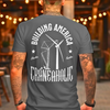 Man with tatoos wearing a gray building american craneaholic renewable energy t shirt with DTG printed design on back with a diner back ground