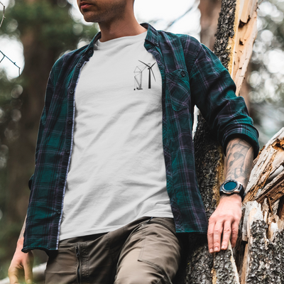 Man with a green and purple flannel in the woods wearing a white undershirt with a crane building a wind turbine design DTG printed on the front