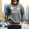 White model with a brown five o clock shadow wearing a gray bella canvas hoodie with a white DTG design printed on the front while standing on a city street