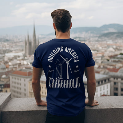 A man looking out over a city skyline with a navy blue building america renewable energy craneaholic t shirt  that has DTG printed back logo.