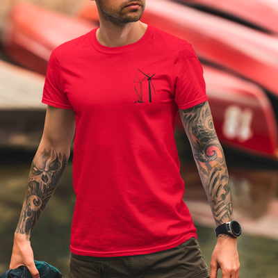 White male with tattoos on both arms wearing a bright red blue collar crane operator t shirt while at a lake