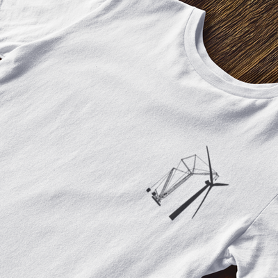 Up close visual of white t shirt laying on a wood floor showcasing DTG printed design of crane erecting a wind turbine